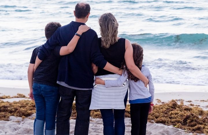 Familie und Kinder Familie steht am Strand und schaut aufs Meer hinaus