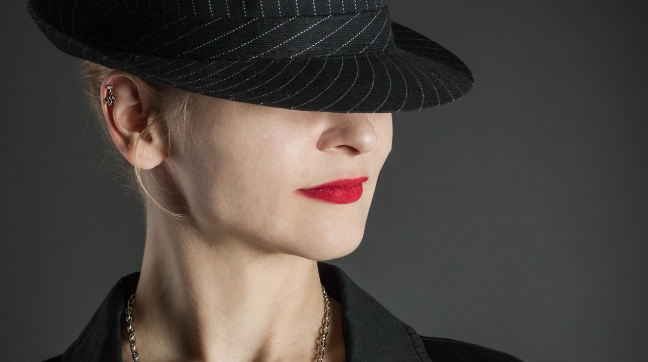 Red Lips Frau mit Hut, rotem Lippenstift und Schmuck, in eleganter Kleidung.